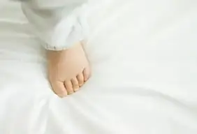 Cropped photo of a Baby's foot on a clean mattress